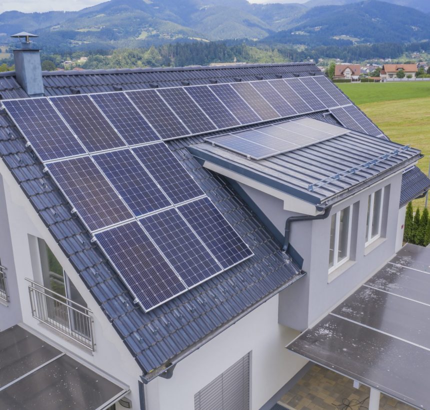 A high angle shot of a private house situated in a valley with solar panels on the roof