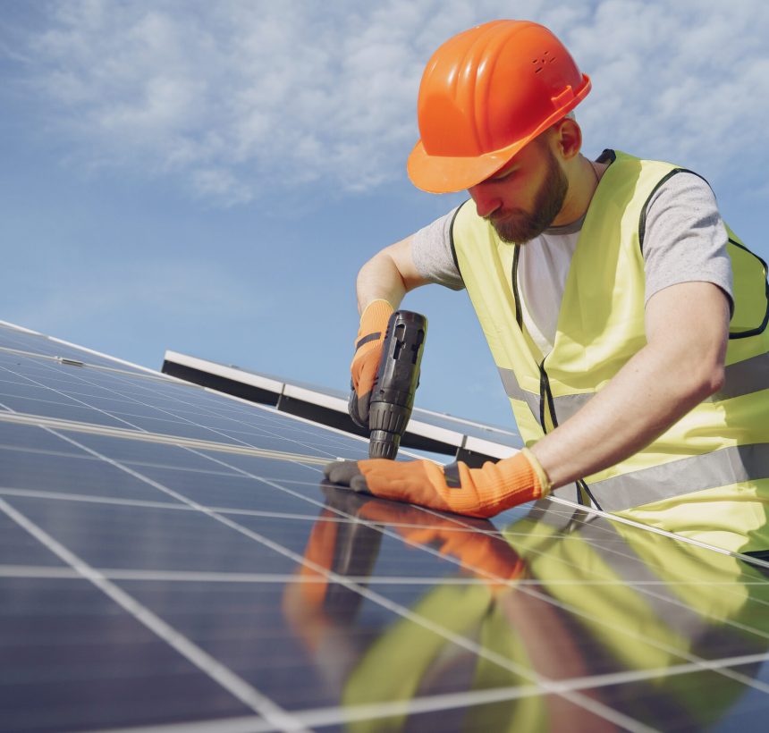 Male worker with solar batteries. Man in a protective helmet. Installing stand-alone solar panel system.
